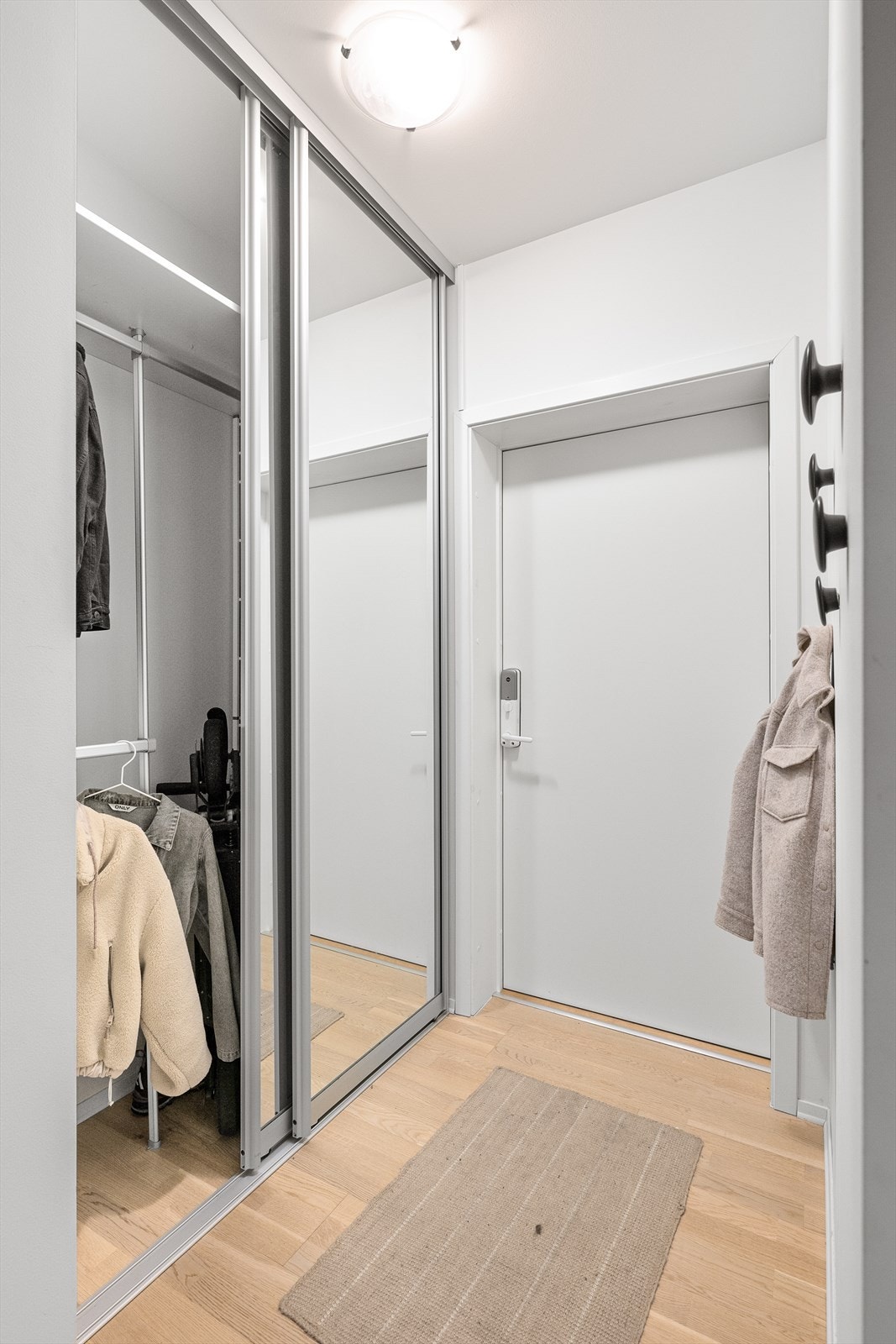 Innbydende entré med parkett på gulv og god plass til oppbevaring i skyvedørsgarderobe. Galleribilde