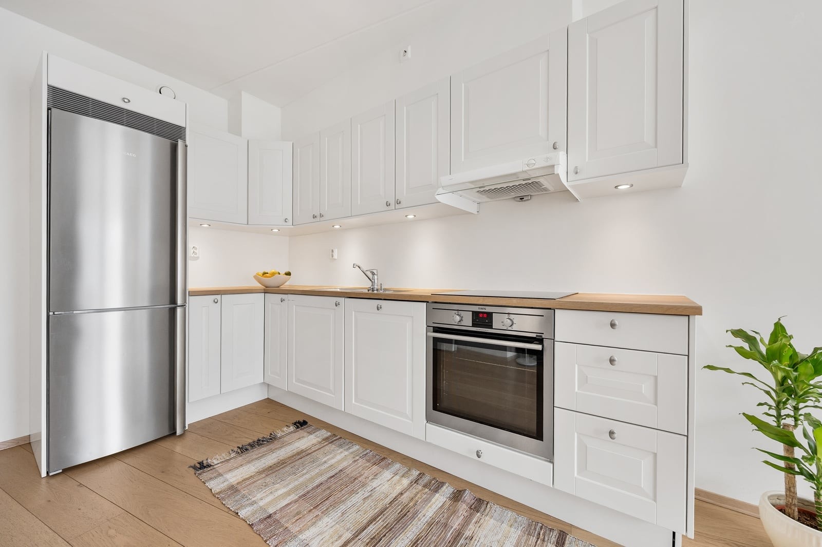 Kjøkkeninnredning med profilerte fronter, heltre benkeplate og integrert platetopp og stekeovn og frittstående kjøl/frys Galleribilde