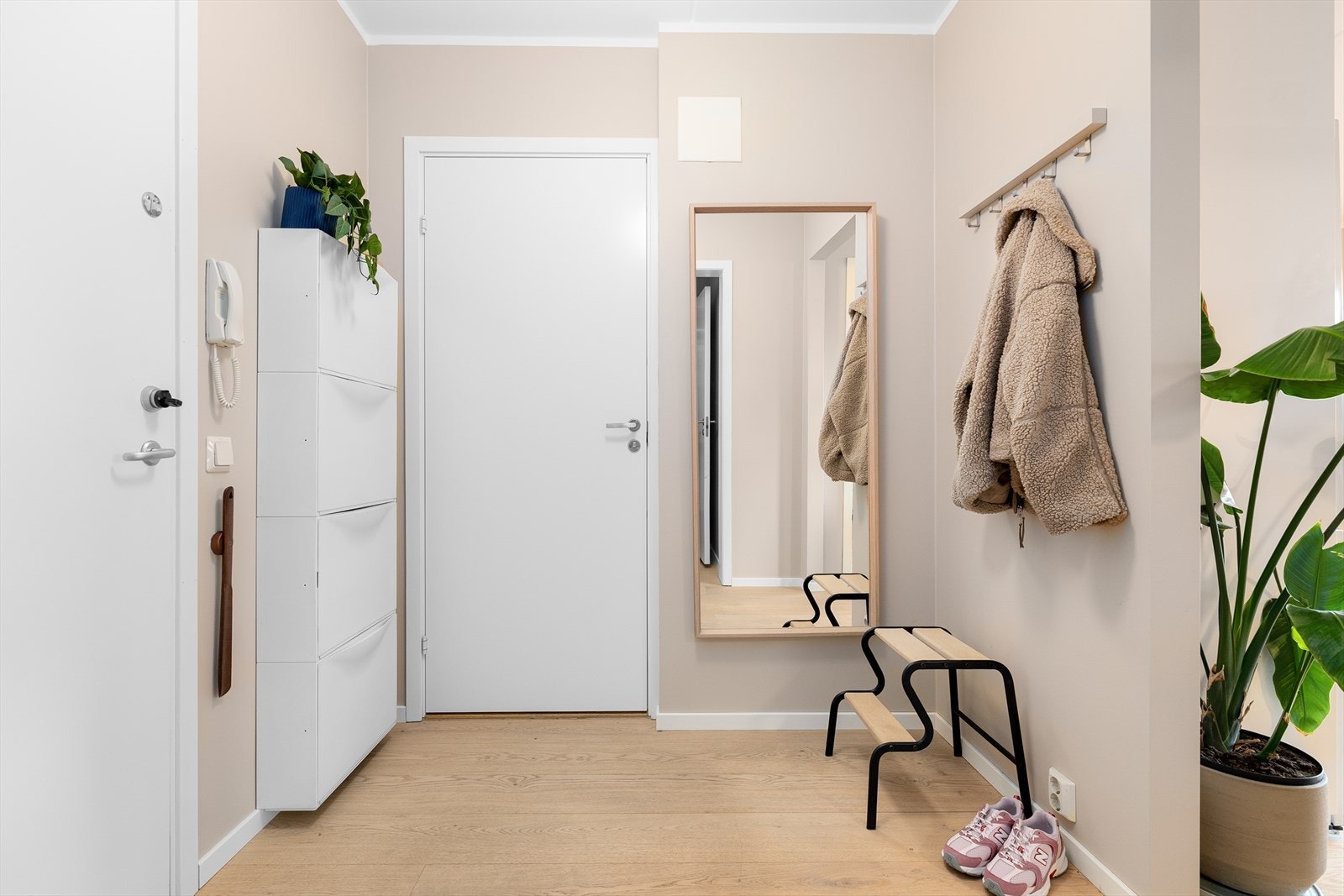 En lys entré med parkett på gulvet og dørtelefon ønsker deg velkommen inn. Galleribilde