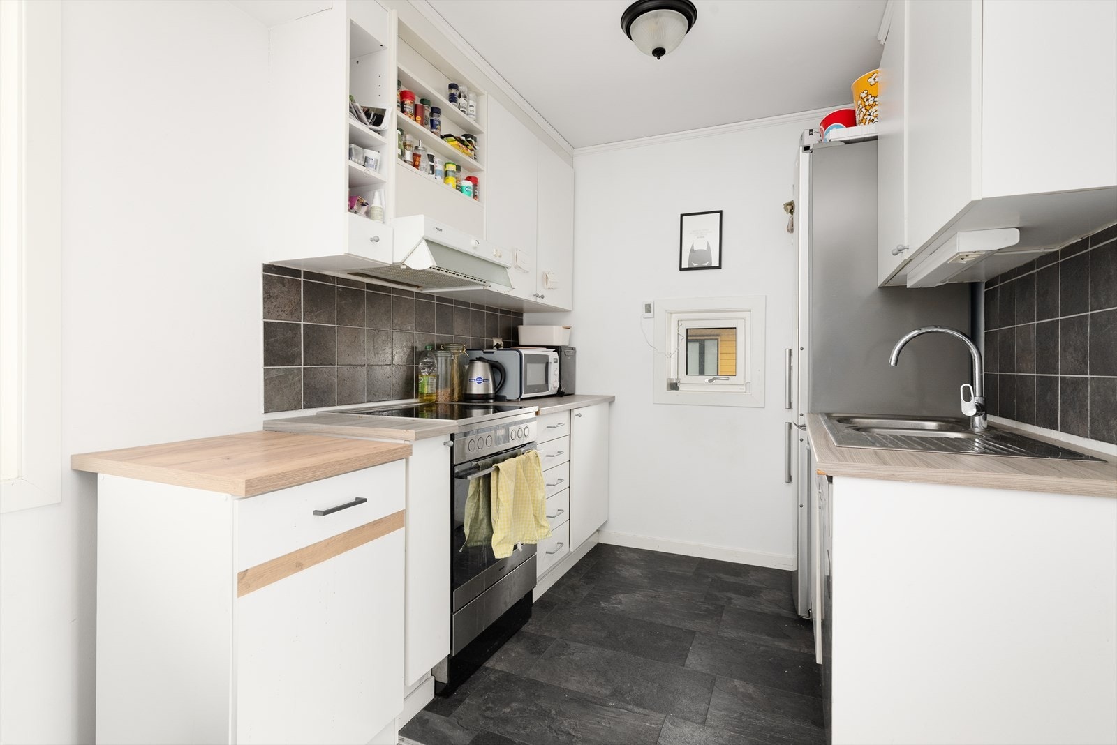 Kjøkkenet har innredning med god skap på begge sider av rommet, med glatte fronter og benkeplate av laminat med flis over. Galleribilde