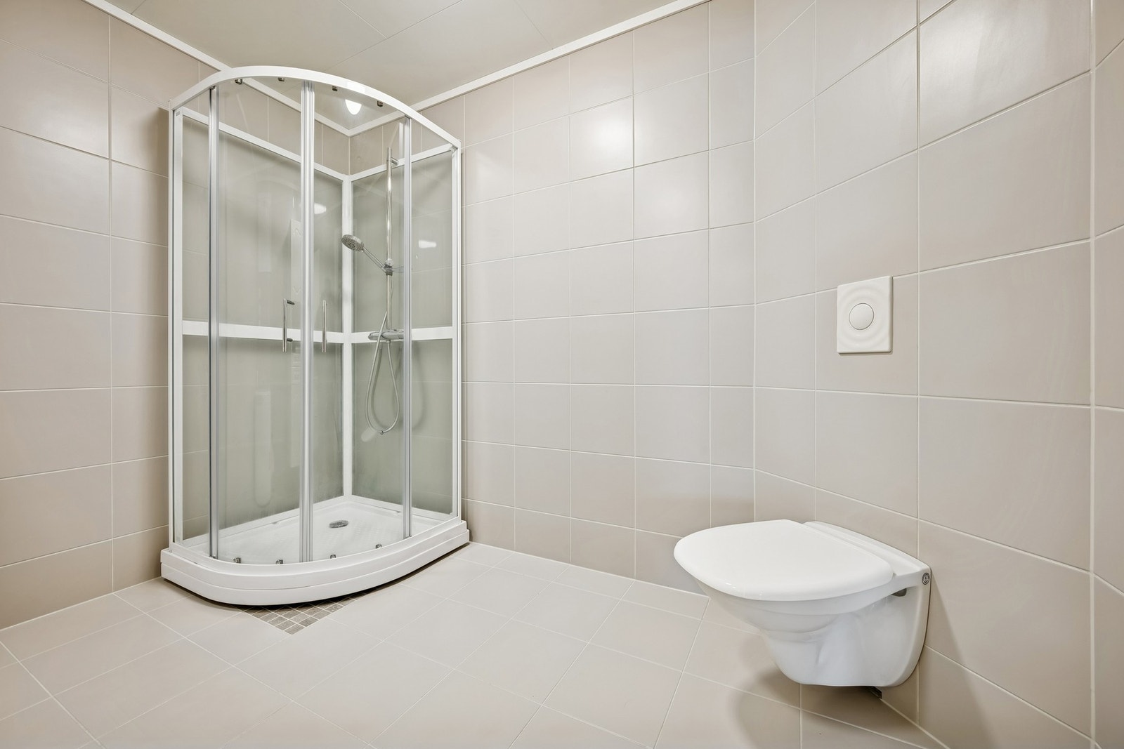 Fint bad med nye fliser fra 2025/26 i lyse, nøytrale toner. Her finner du både dusjkabinett og vegghengt toalett Galleribilde