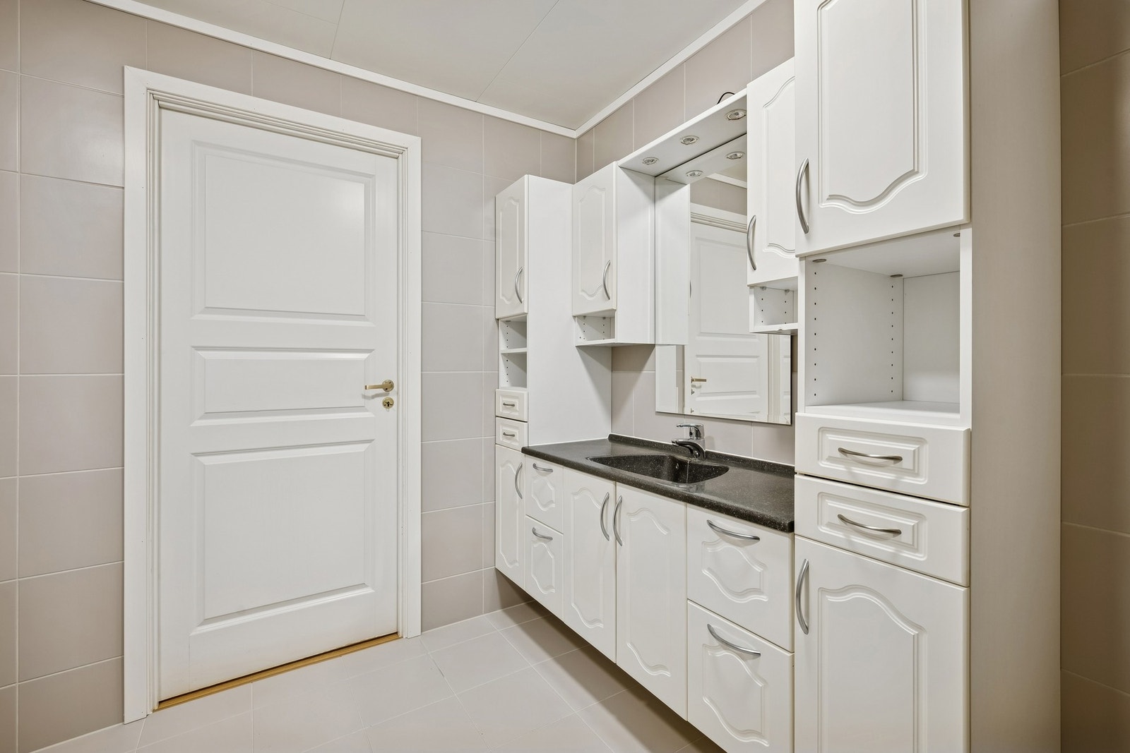 Badet har en romslig og stilren baderomsinnredning med stor benk/vask i helstøpt utførelse og godt med skapplass Galleribilde