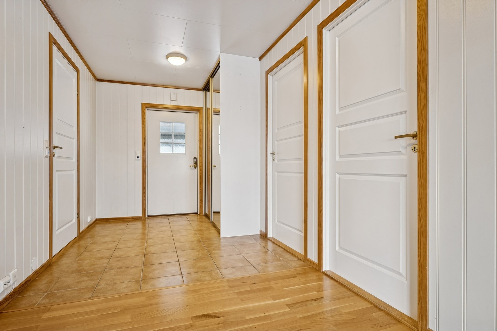 Lys og romslig hall med varme i det flislagte gulvet ved inngangspartiet og plassbesparende skyvedørsgarderobe Galleribilde