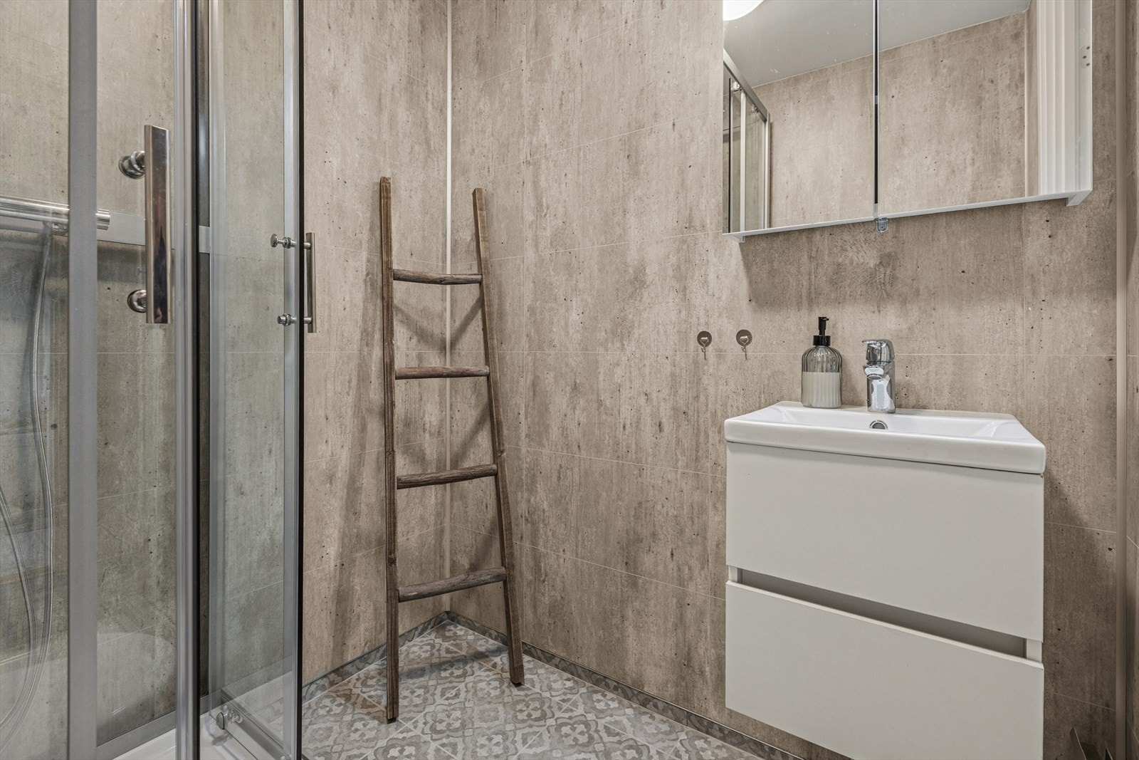 Badet er utstyrt med dusjkabinett, gulvstående toalett og en lys og moderne baderomsinnredning. Galleribilde