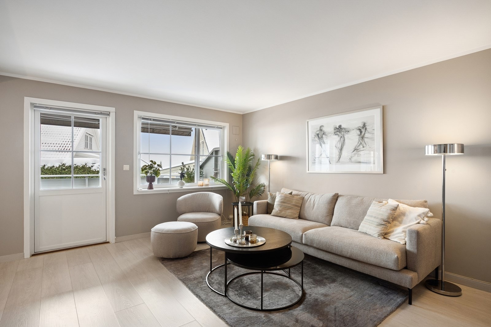 Klassisk enstavs laminat på gulvet og delikate gråbeige vegger gir et tidløst uttrykk, mens store vindusflater og terrassedør slipper inn rikelig med dagslys Galleribilde