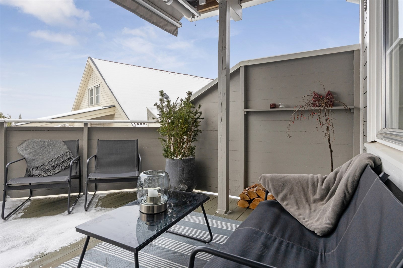 Romslig, delvis overbygget terrasse med stilrent tregulv, moderne levegg og rekkverk med liggende kledning - et lunt og trivelig uteområde Galleribilde