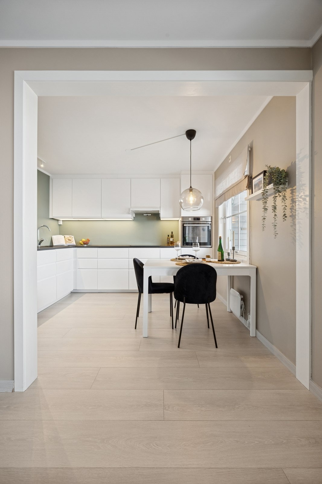 Over kjøkkenbenken er veggene malt i en dus og delikat grønnfarge. Det er god belysning både i form av lys under overskapene og en spotskinne i himlingen på den ene siden Galleribilde