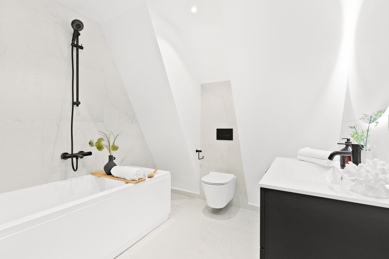 Baderom utstyrt med varmekabler, downligts, badekar, vegghengt toalett og servantinnredning samt rundt speil med integrert belysning. Galleribilde