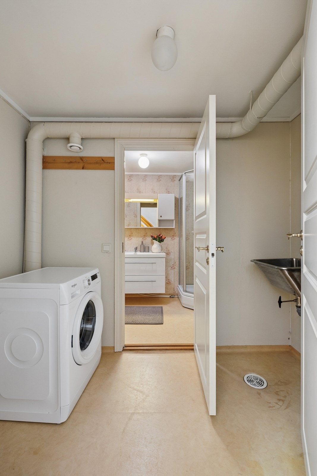 Separat vaskerom med belegg på gulvet og plater på veggene. Enkelt innredet med en utslagskum og opplegg for vaskemaskin. Galleribilde