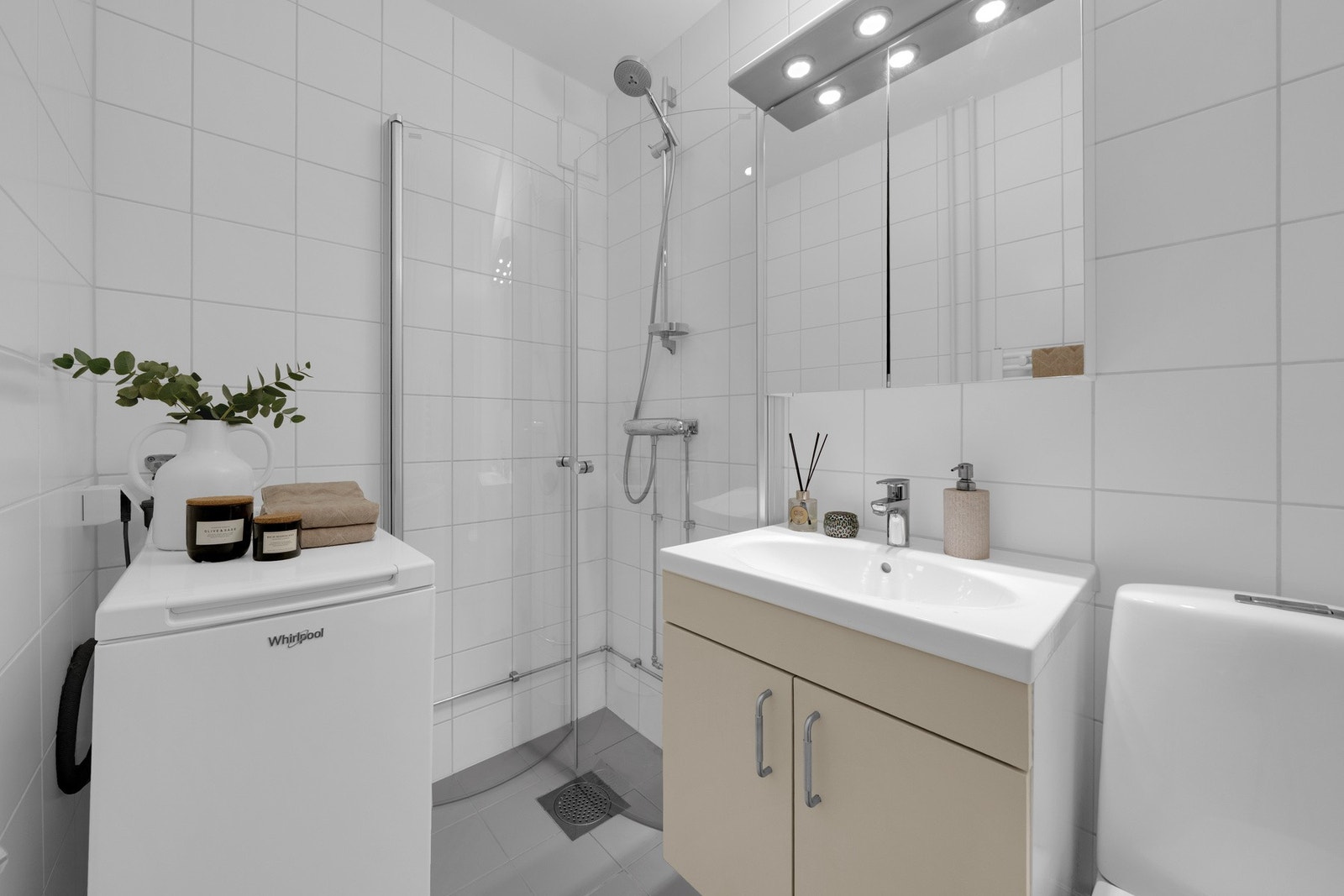 Badet er utstyrt med innredning med to skuffer og servant, speil med belysning over, toalett og dusjhjørne med innfellbare dusjdører. Galleribilde