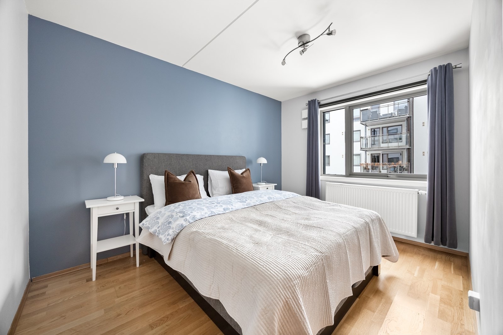 Lunt og romslig soverom med parkettgulv og malte overflater i hvitt og blått. Galleribilde