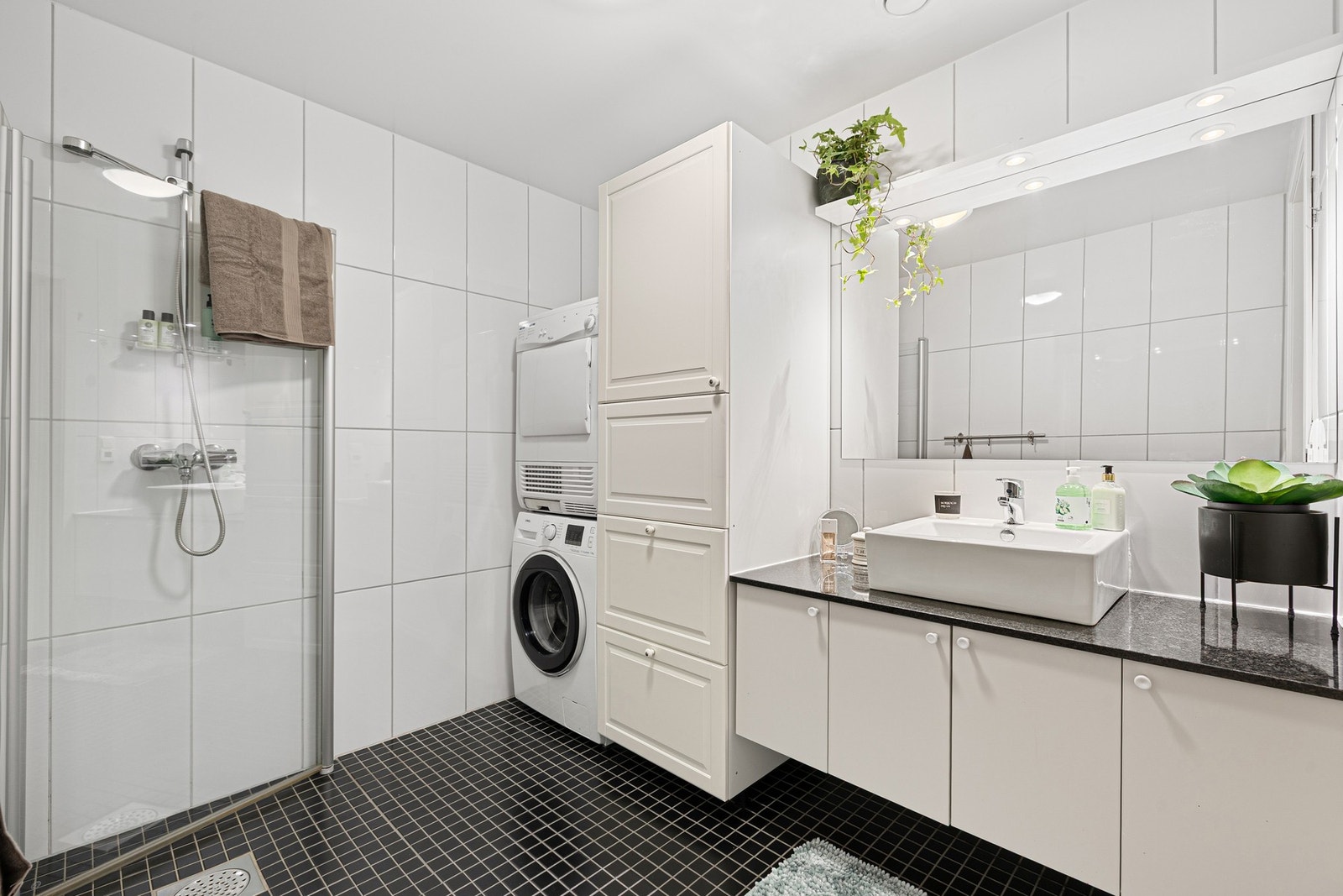 Utstyrt med innfellbare dusjdører, veggmontert wc, servant, servantskap, opplegg for vaskemaskin og mekanisk avtrekk. Galleribilde