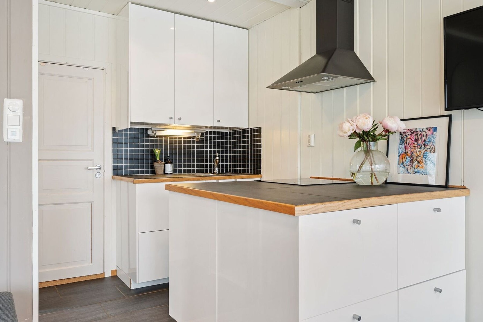 Lys kjøkkeninnredning med halvøy og skap på begge sider som gir ekstra lagringsplass. Galleribilde