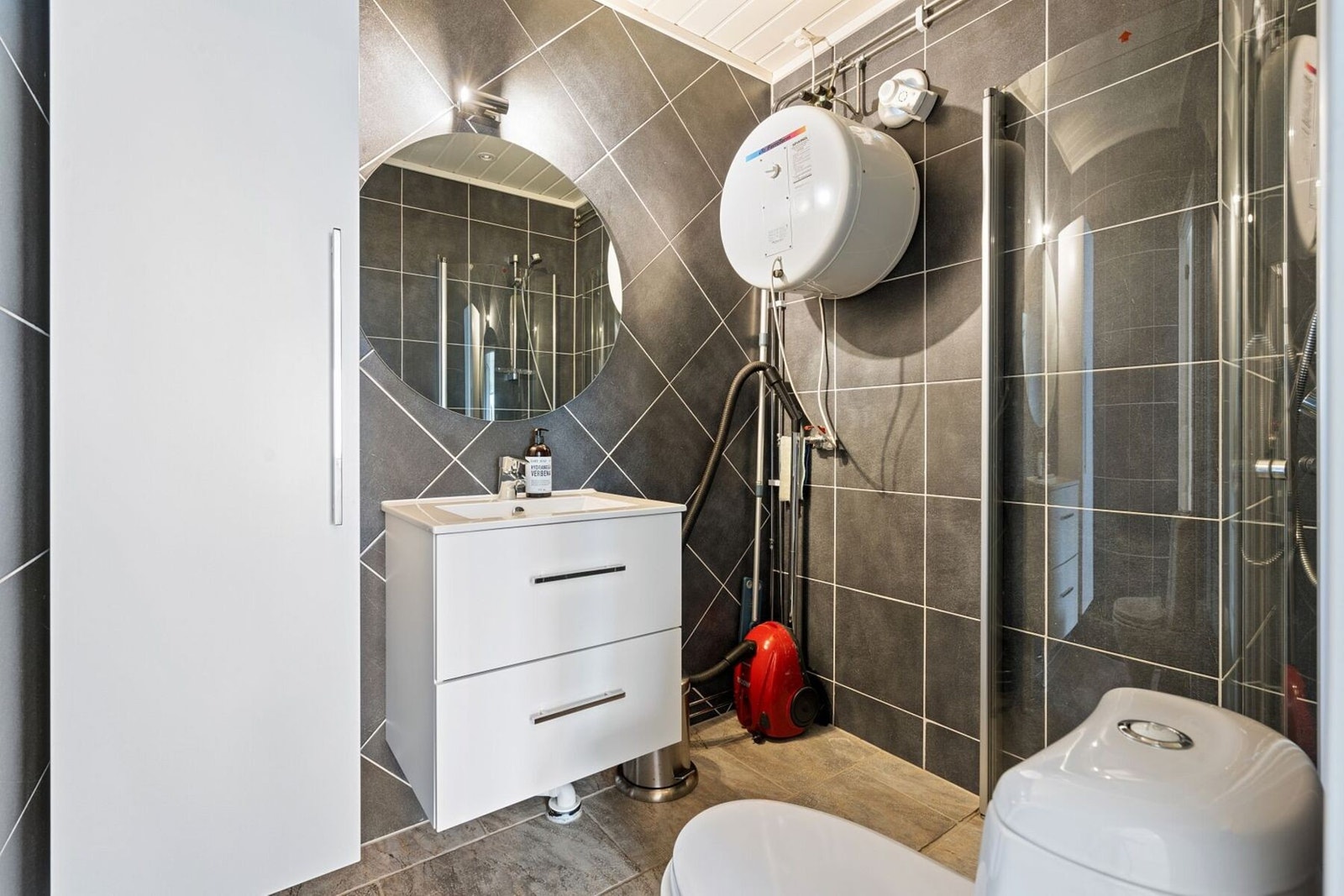 Bad med toalett, dusjhjørne, baderomsinnredning og vask. Galleribilde