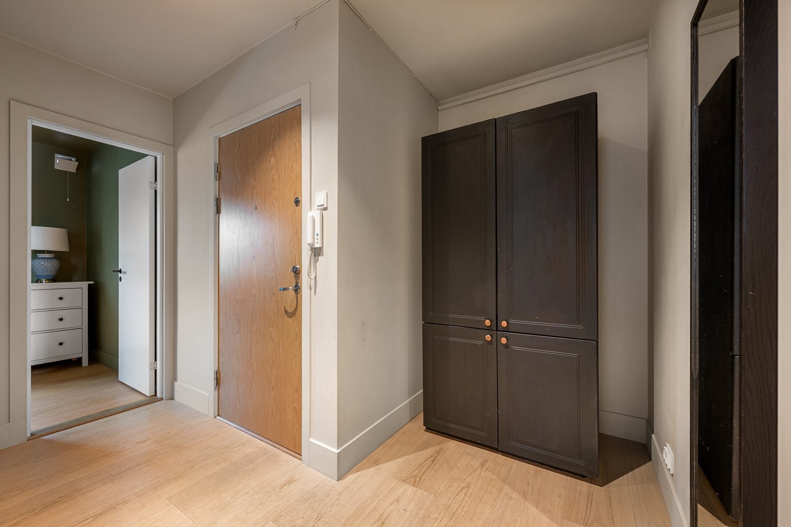 Velkommen inn! Her blir du møtt av en innbydende entré som gir et umiddelbart godt førsteinntrykk av leiligheten. Det er god plass til knagger, skap hyller for sko og yttertøy. Det er i tillegg montert dørtelefon med åpner. Galleribilde