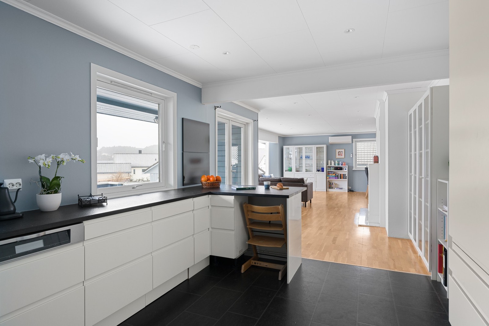 Kjøkkeninnredning med hvite slette fronter og mørke benkeplate i stein. Galleribilde