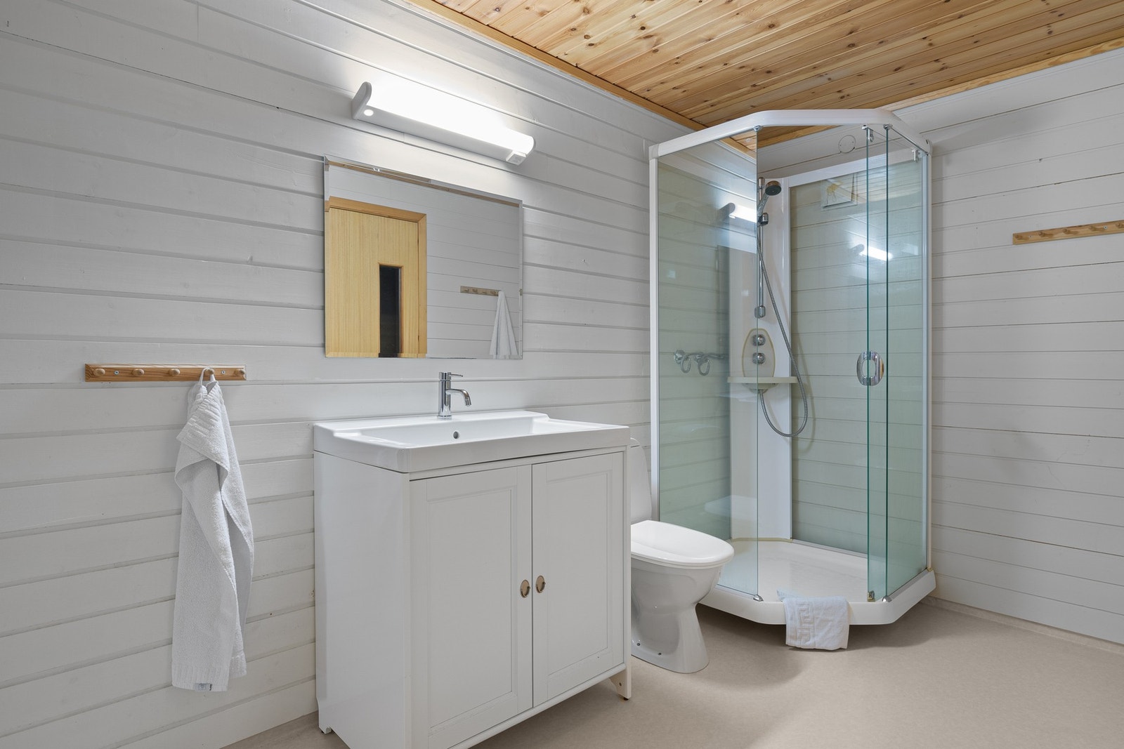 Badet i kjeller har belegg på gulv og trepaneler på vegg og tak. Galleribilde