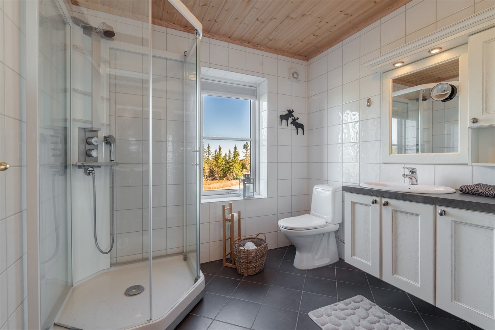 Hytta har helfliset bad med varmekabler i gulvet. Her er en pen, lys innredning med nedfelt servant samt overskap og lys over speilet. Badet er også innredet med dusjkabinett og toalett. Galleribilde