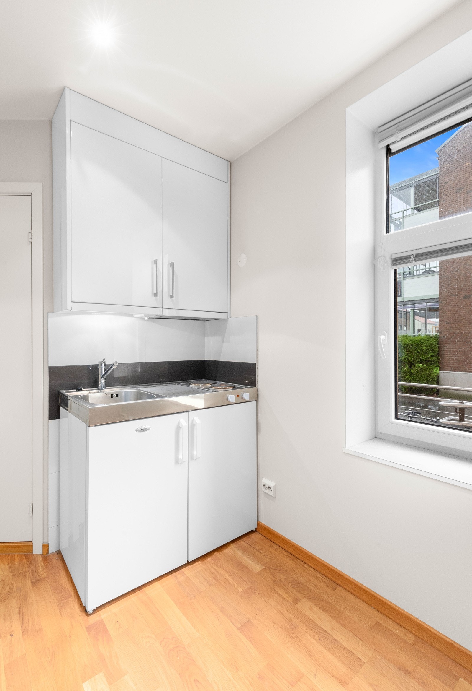 Enkelt hybelkjøkken med stekeplate og kjøleskap. Galleribilde