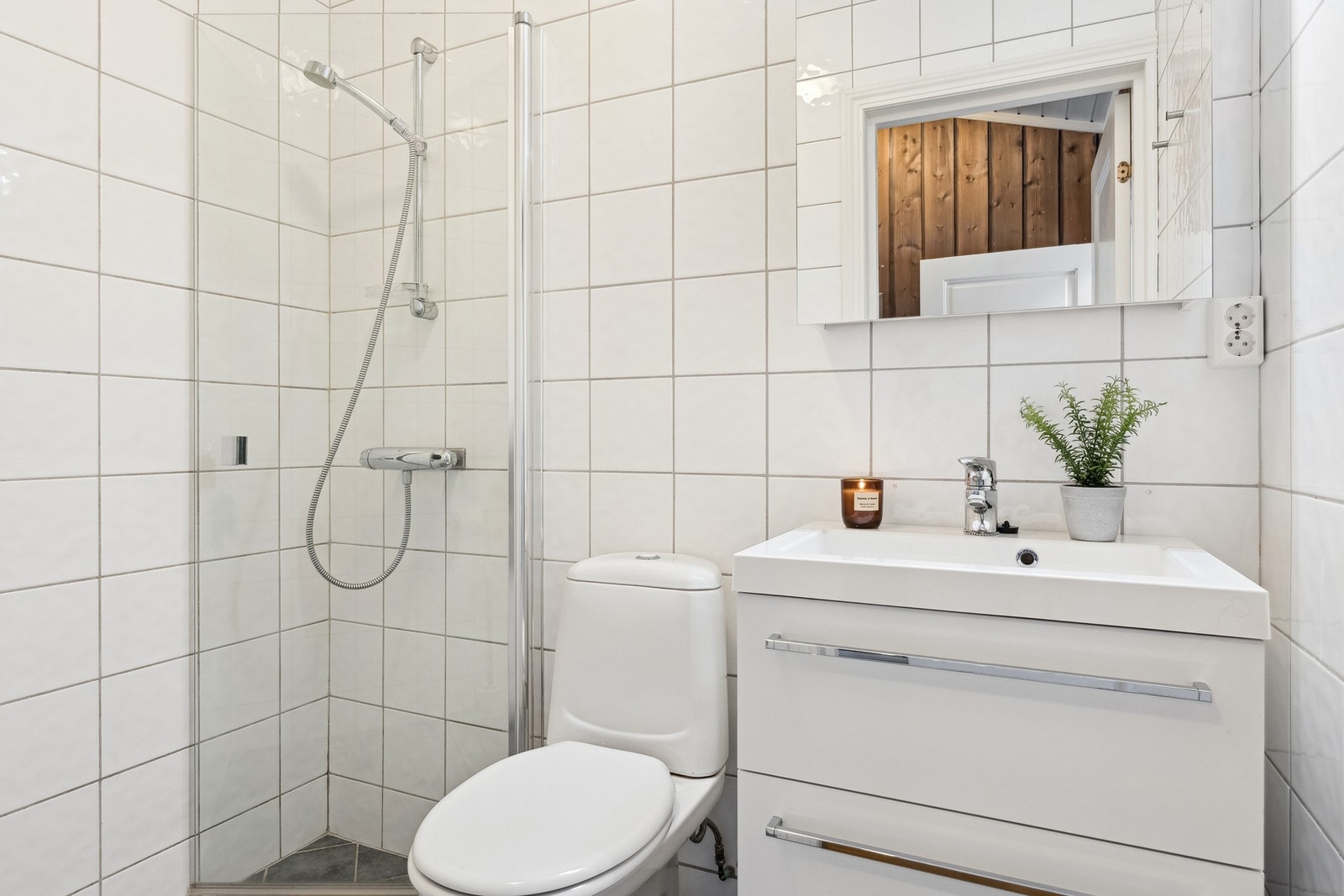 Lyst, flislagt bad med baderomsinnredning, toalett og dusj. Galleribilde