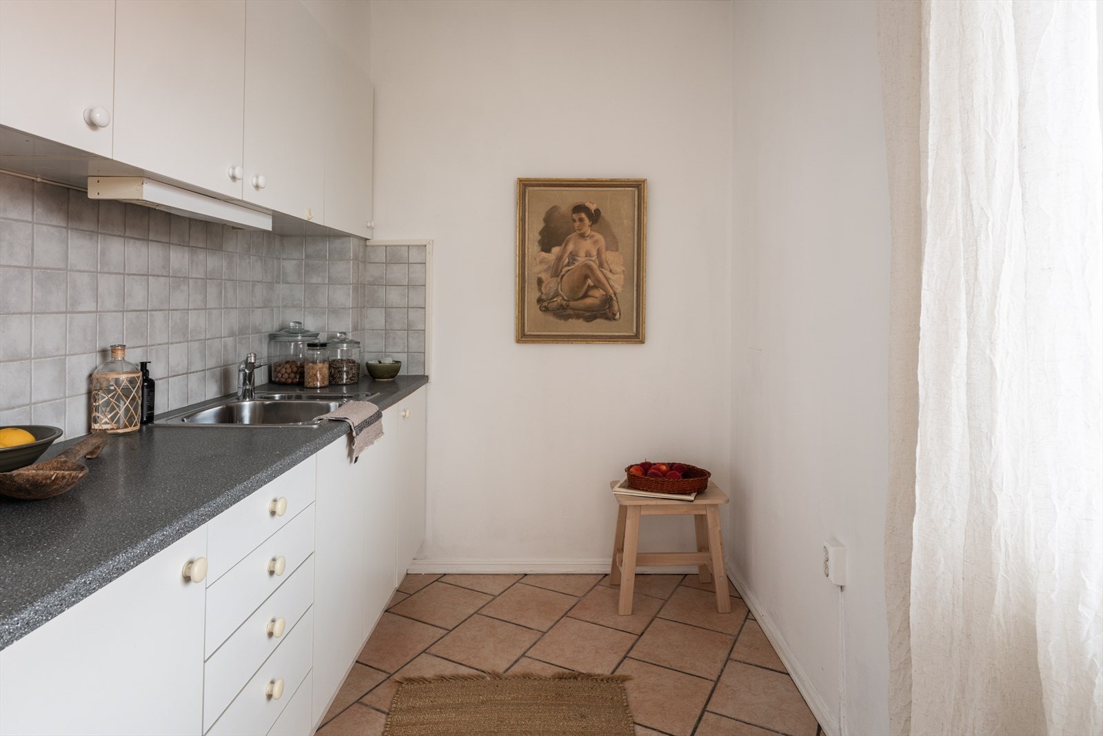 Innredningen består av nøytrale, hvite fronter, fliser på bakvegg, laminert benkeplate og det er plass til frittstående hvitevarer. Galleribilde