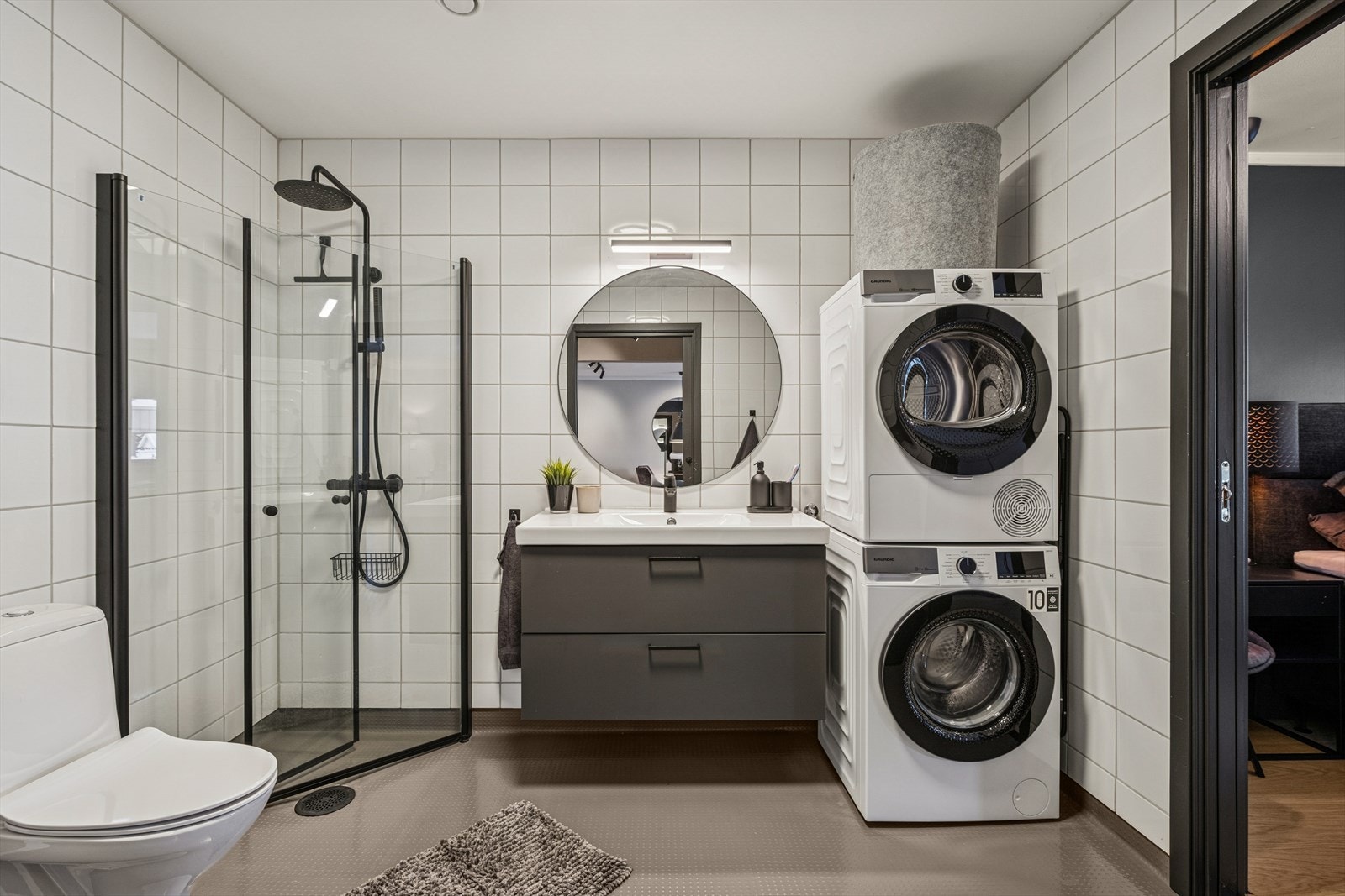 Pent bad utstyrt med dusjhjørne med regndusjarmatur og hånddusj, gulvstående toalett og opplegg for vaskemaskin/tørketrommel. Galleribilde