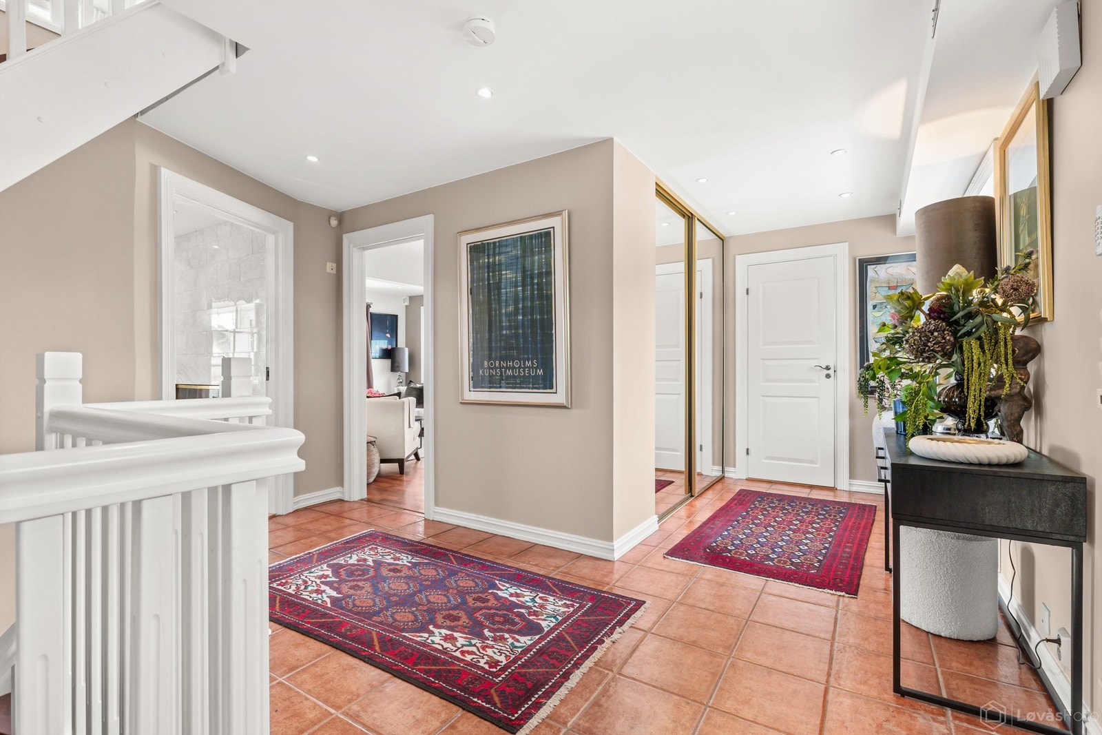 Romslig entré/hall med gulvfliser med gulvvarme og skyvedørsgarderobe med god plass til yttertøy Galleribilde