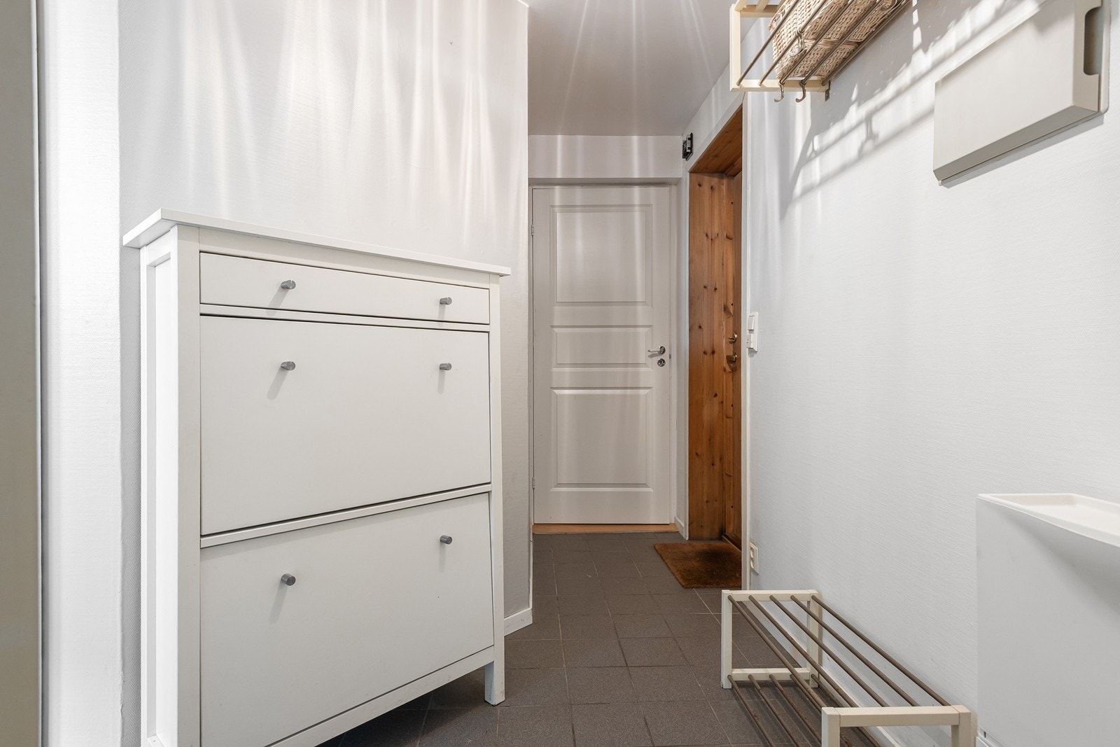 Entré/gang med gulvfliser med gulvvarme og plass til oppheng for yttertøy. Adkomst til entréen via utvendig kjellertrapp Galleribilde
