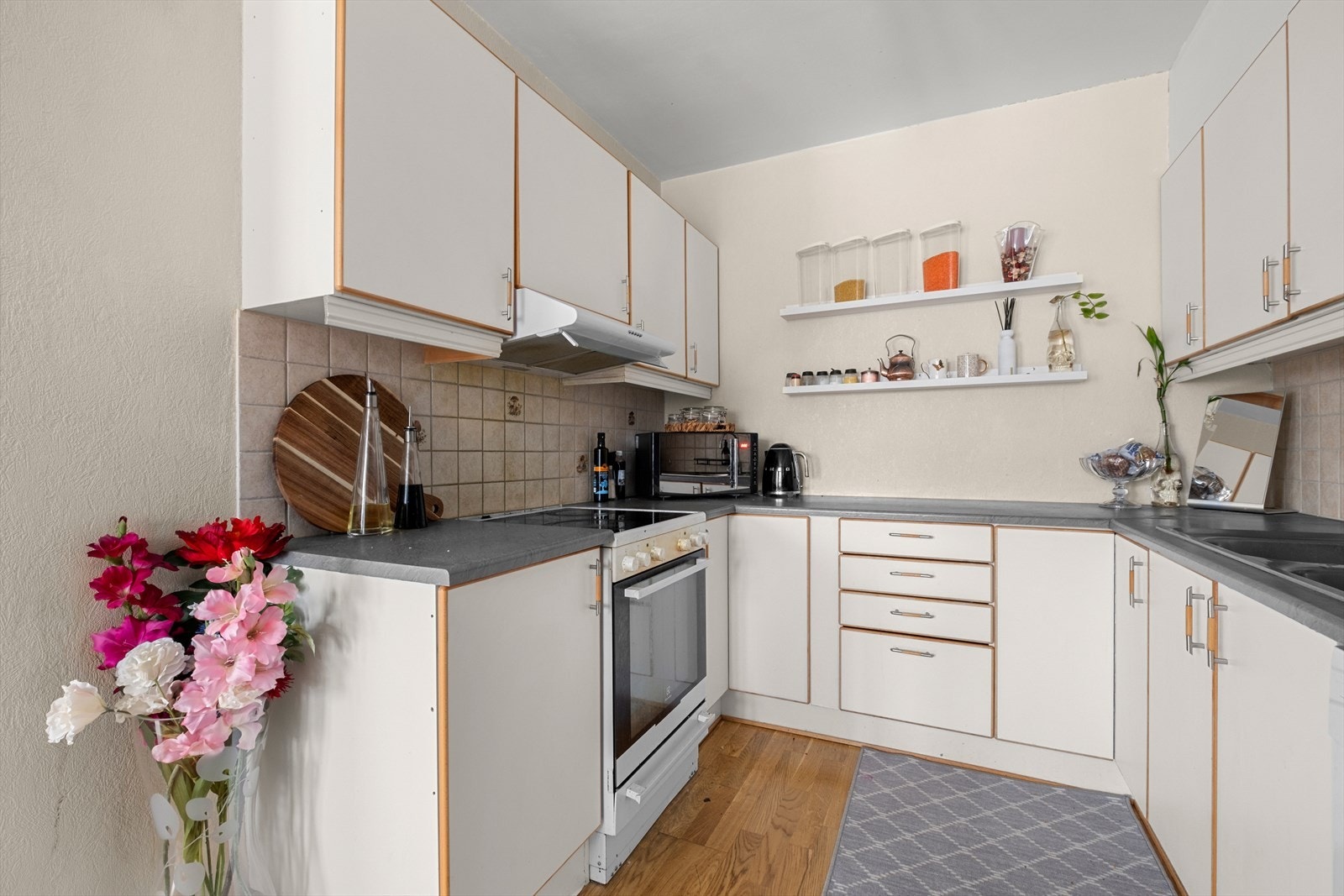 Pent kjøkken med hvite plane fronter og laminerte benkeplater, et tidløst uttrykk som passer de fleste stiler. Galleribilde