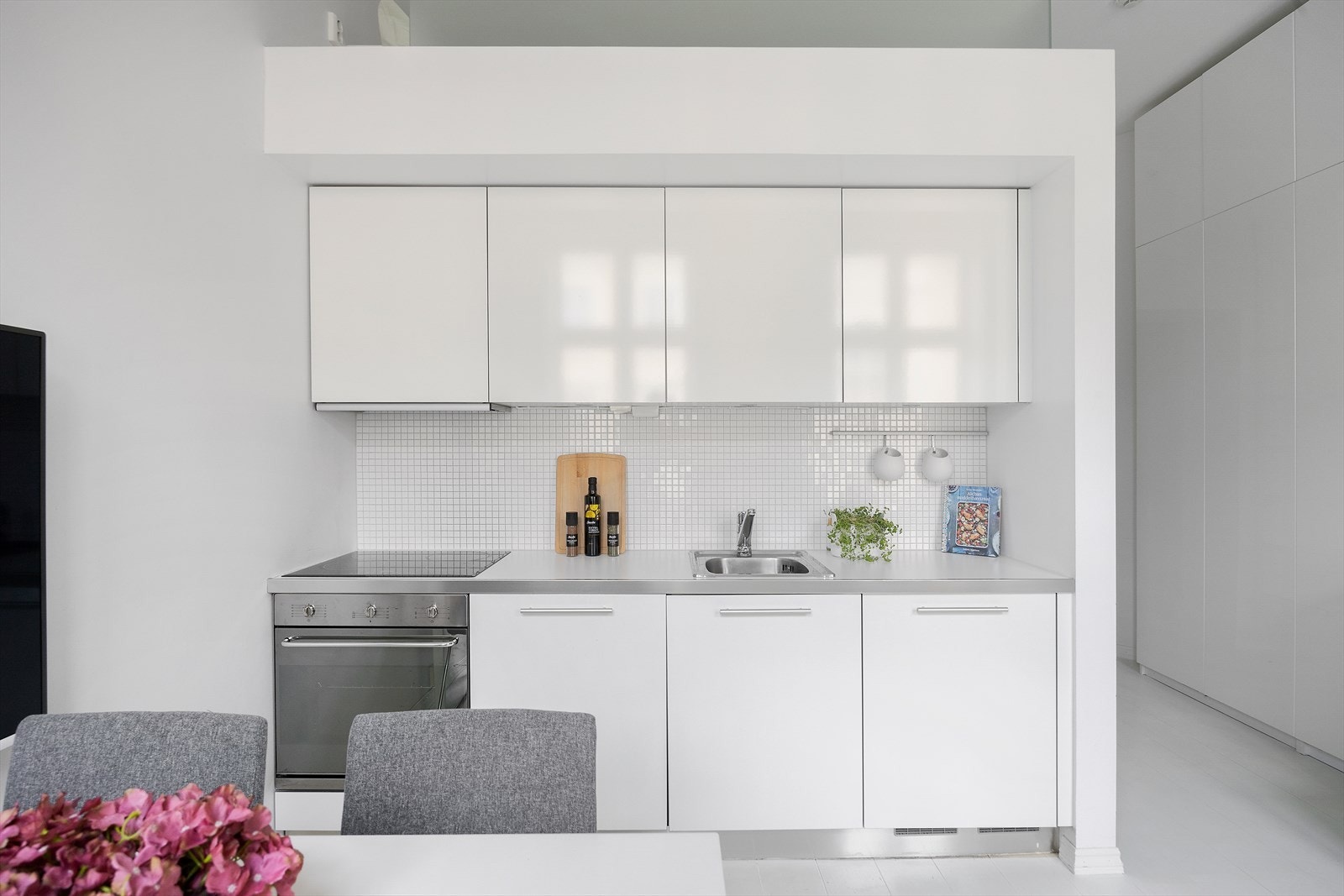 Lyst og tidløst kjøkken med glatte fronter, laminat benkeplater, nedfelt oppvaskkum i stål med ettgreps armatur fra Oras, samt integrert stekeovn, platetopp, oppvaskmaskin og kjøleskap. Galleribilde