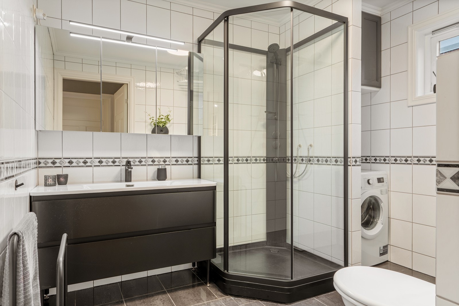 Flott flislagt bad med vegghengt servant og vaskemaskin/tørketrommel. Galleribilde