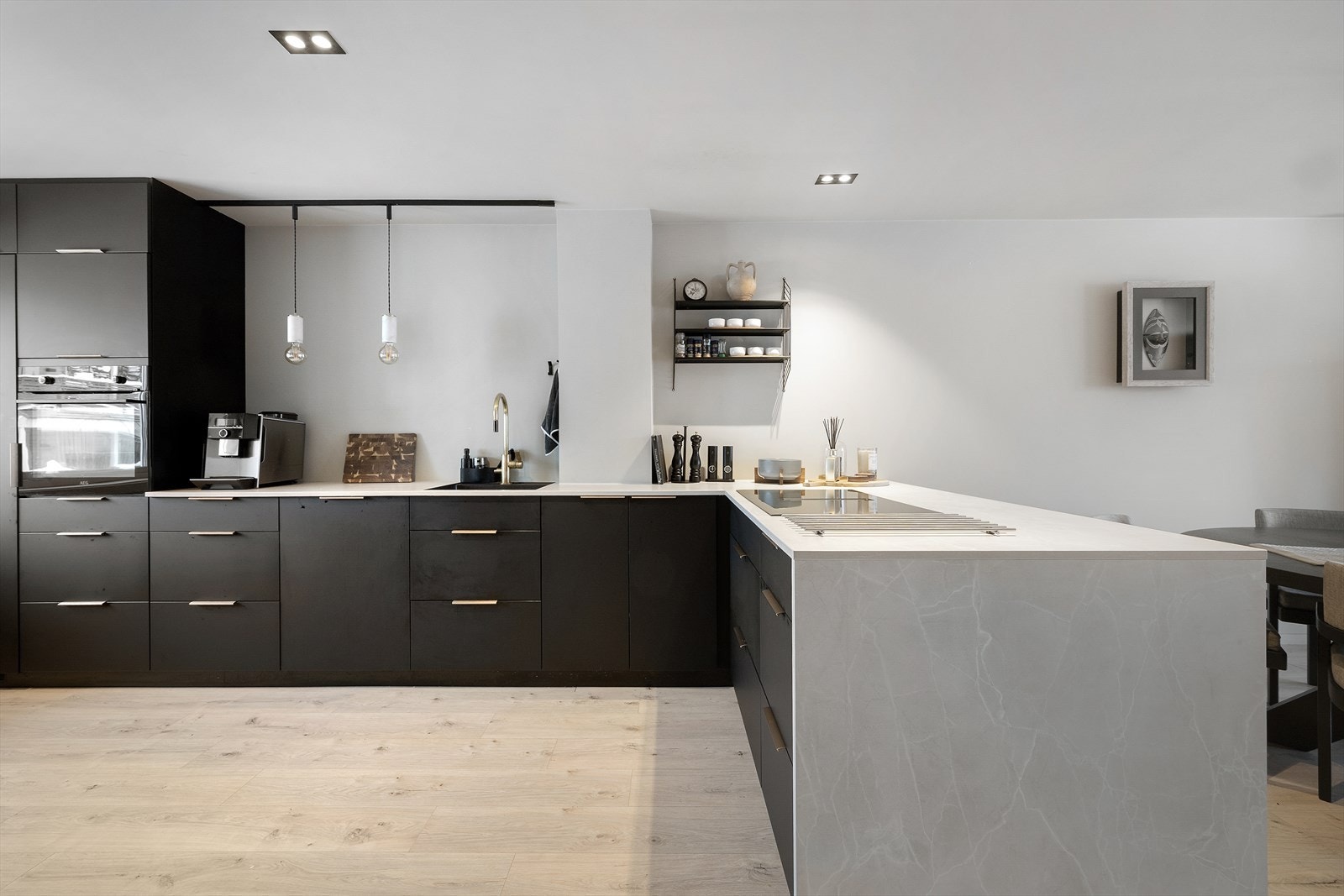 Et sosialt utformet kjøkken med kokesonen vendt mot spisestuen, rikelig med benkeplass og hvitevarer av god kvalitet. Galleribilde