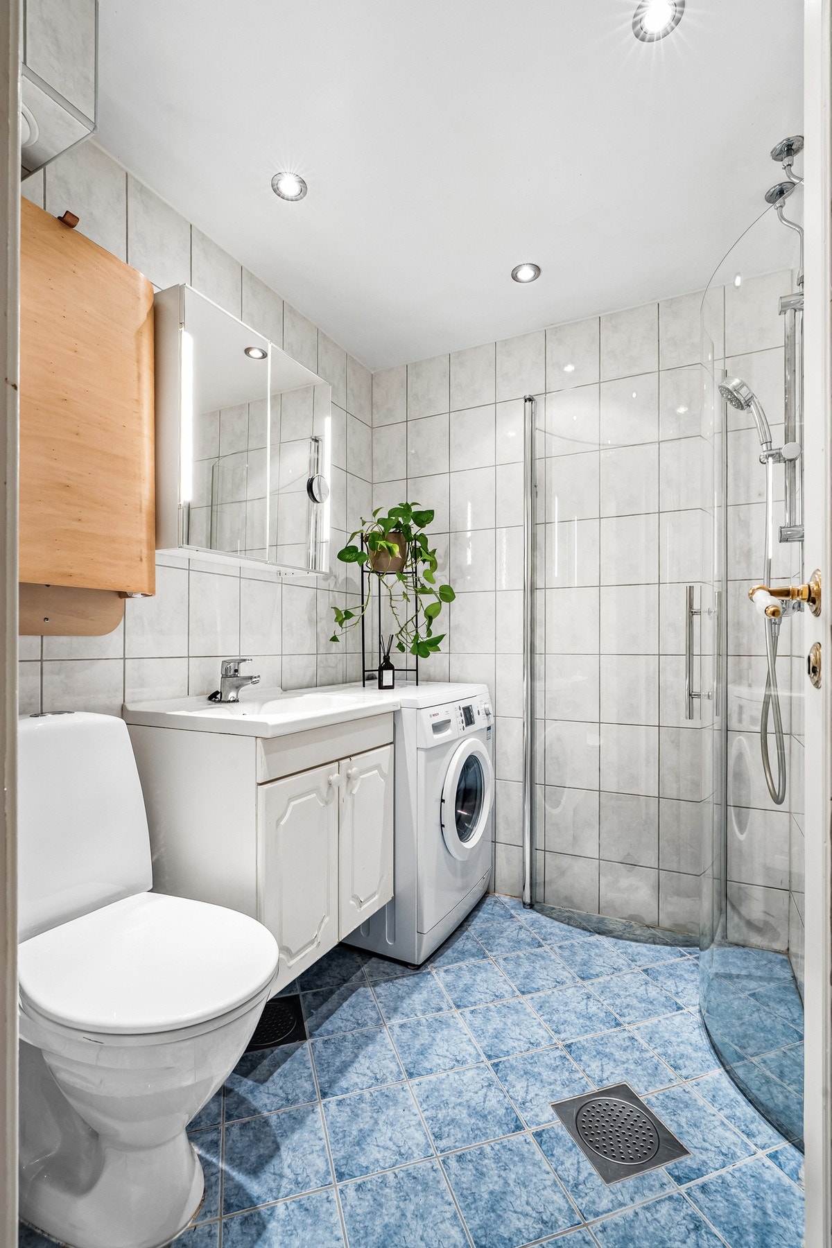 Badet ble rehabilitert i regi av borettslaget i 2008/09. Dusjsonen er adskilt med to buede skyvbare glassdører. Det er varme i gulv og opplegg for vaskemaskin. Galleribilde