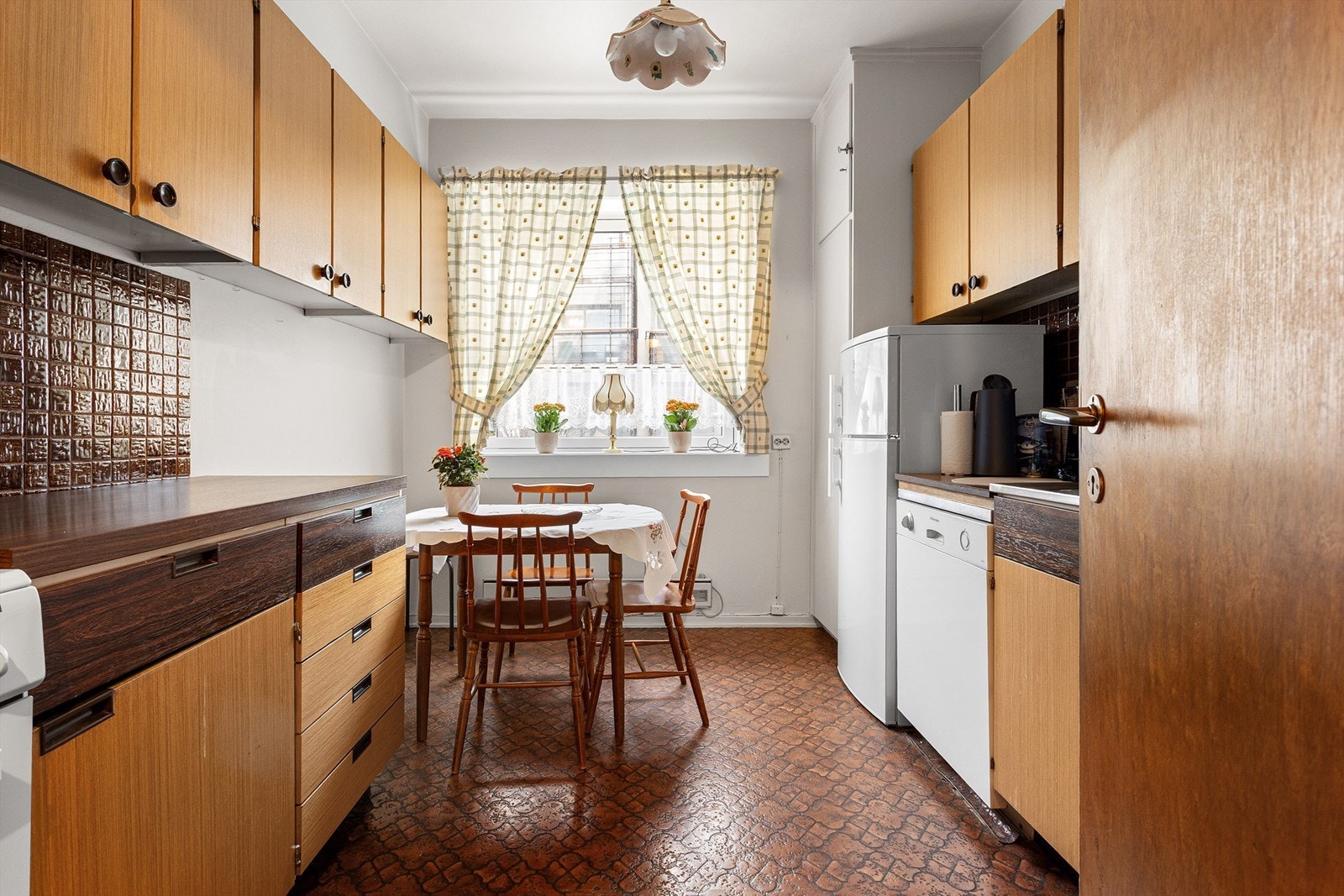 Kjøkkenet har en eldre innredning med glatte fronter og benkeplate i laminat med nedfelt vask. Galleribilde