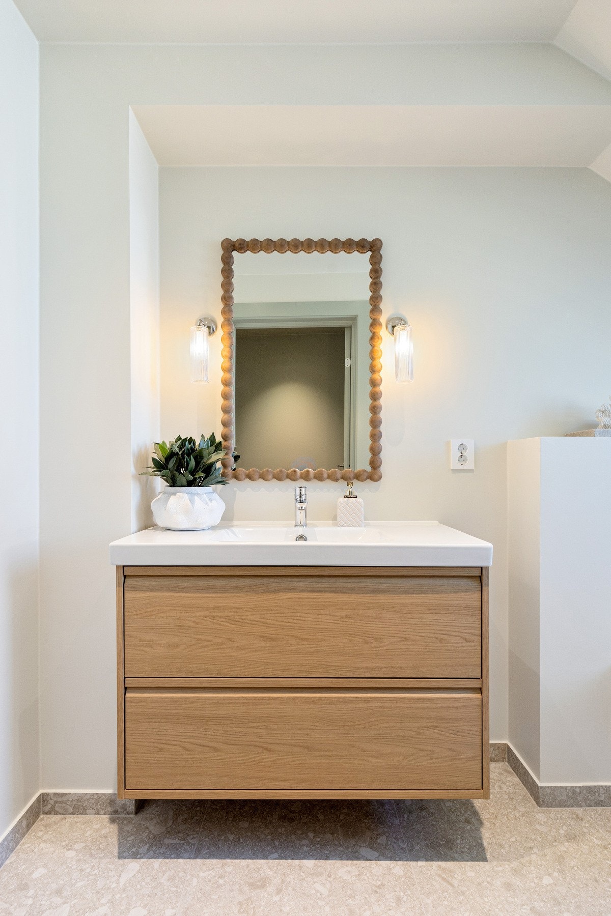 Badet er innredet med vegghengt toalett, dobbel servant og dusjsone med glassdør. Galleribilde