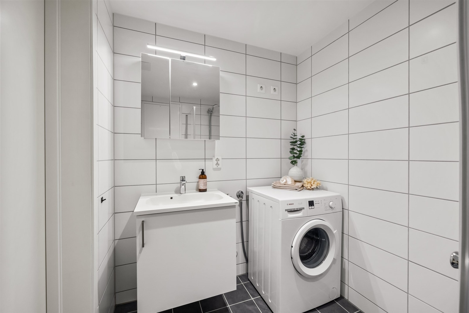 Badet er utstyrt med vegghengt toalett, dusjhjørne og servant med speilskap. Galleribilde