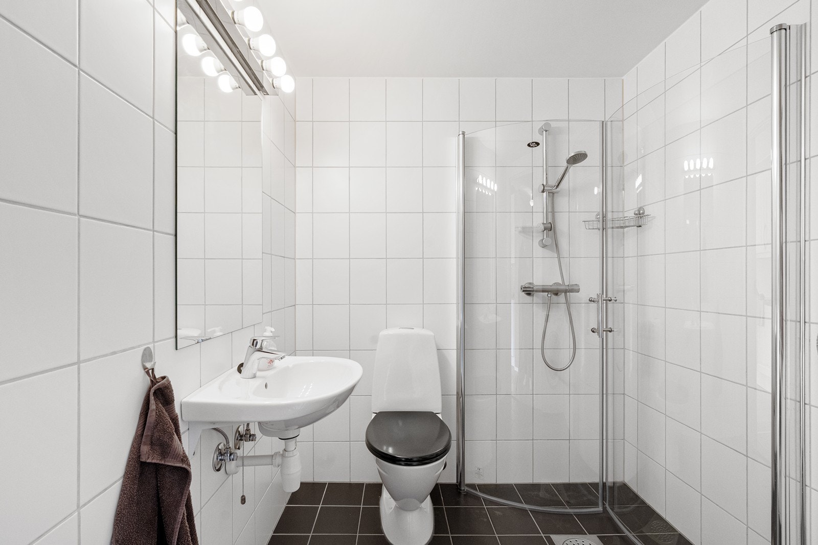 Bad/vaskerom har varmekabler i gulv og fremstår som funksjonelt innredet med baderomsinnredning med nedfelt servant, toalett og dusjhjørne med dusjvegger. Galleribilde