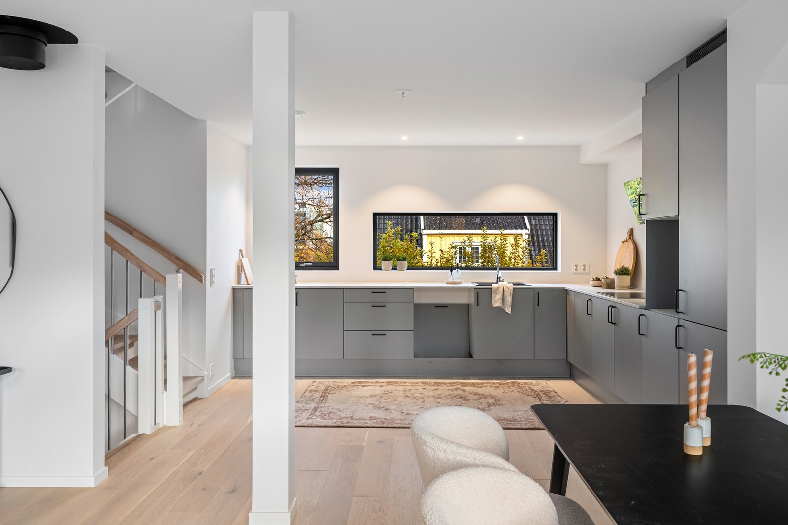 Moderne åpen løsning med trapp og kjøkken i gråtonet design - gir fleksible møbleringsmuligheter og naturlig flyt mellom etasjene. Bildene er fra naboleilighet (15B), med identiske løsninger og materialvalg. Galleribilde
