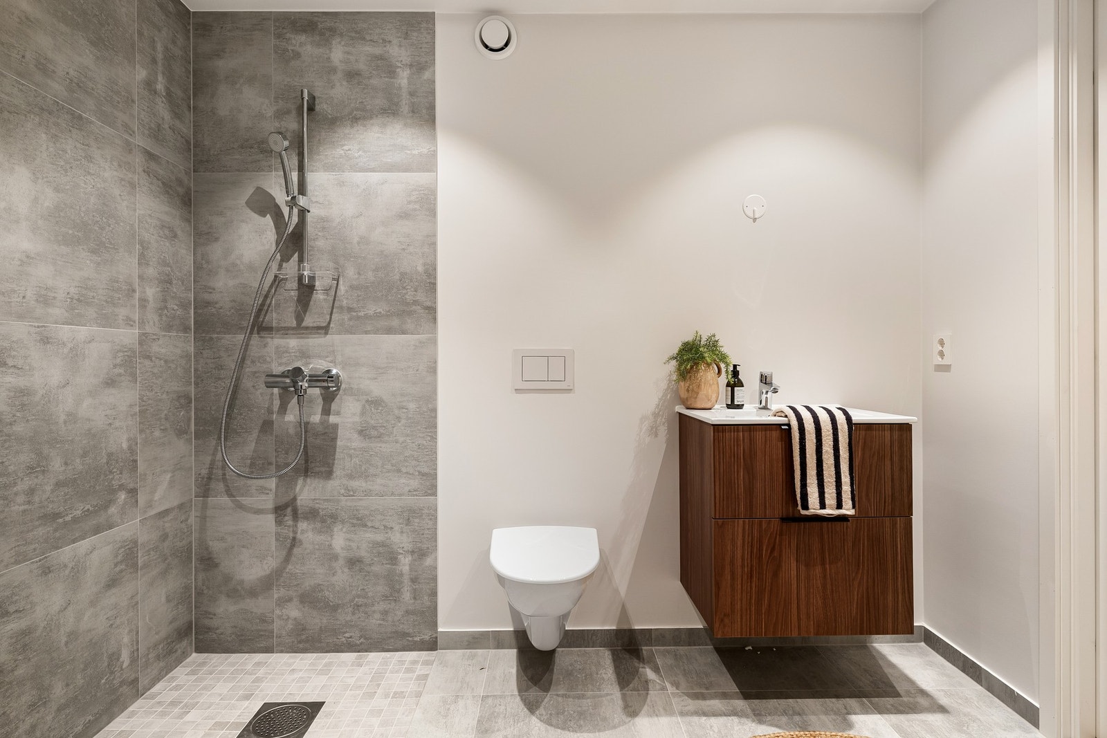 Moderne baderom med stor dusj, vegghengt toalett og elegant servantmøbel - skaper spa-følelse og praktisk hverdag. Bildene er fra naboleilighet (15B), med identiske løsninger og materialvalg. Galleribilde