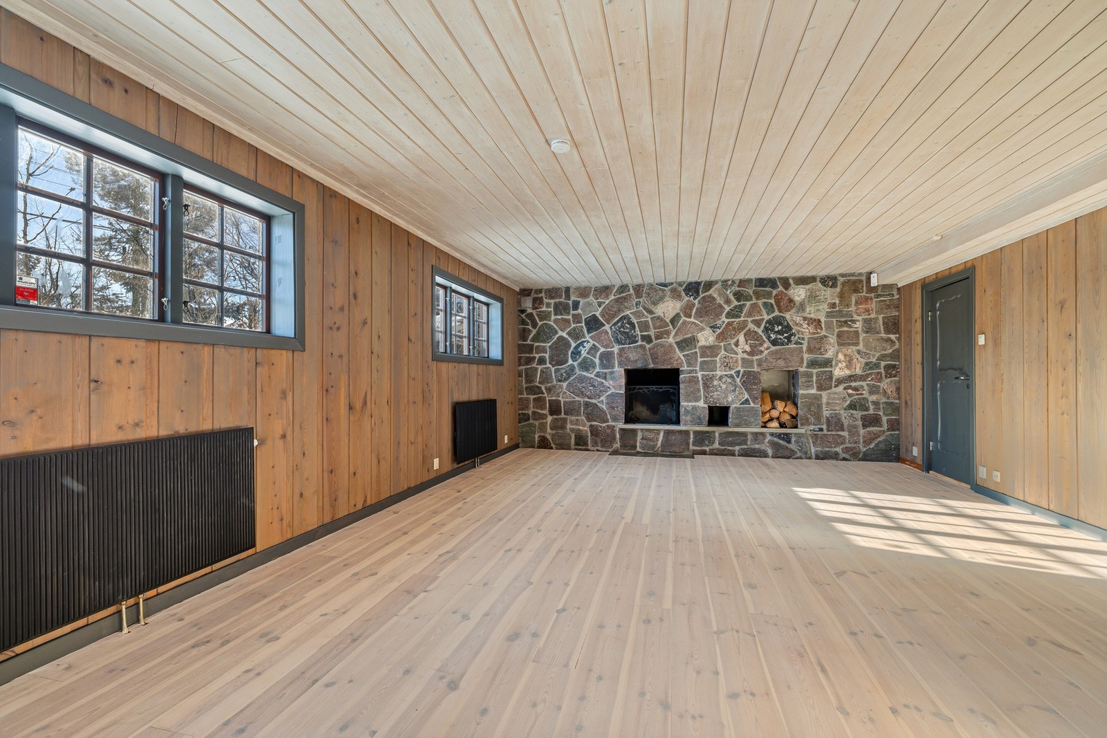 Dekorativ peisløsning med naturstein, åpen grue og rom for vedlagring Galleribilde