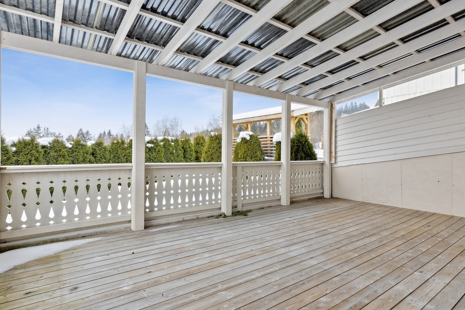 Terrassen har et solid tregulv og rekkverk med dekorative detaljer. Galleribilde