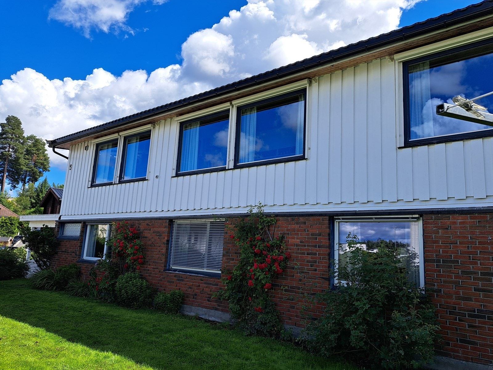 Selgers eget sommerbilde av hagen viser en pent opparbeidet uteplass med rikelig beplantning. Her ser man også de utvendige kassettløsningene med screen og persienner. Galleribilde