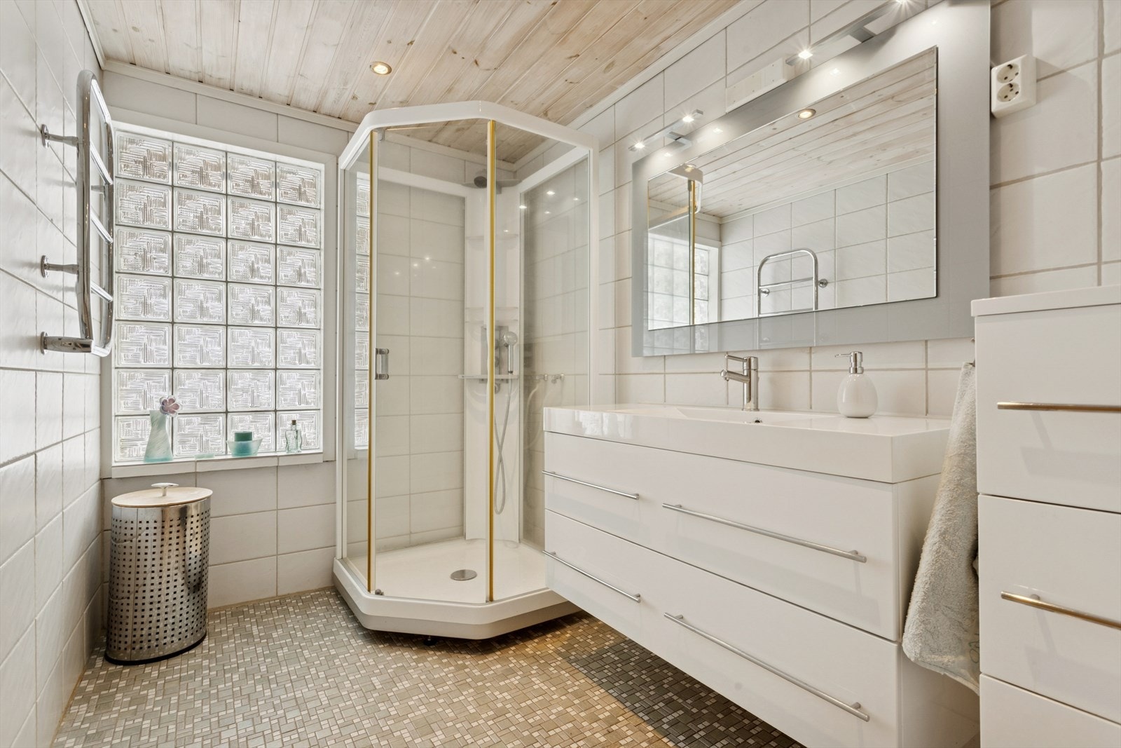 Badet ble pusset opp i 2006 og fremstår som et lyst og funksjonelt rom med fliser på både gulv og vegger. I himlingen er det montert downlights som gir god og jevn belysning, og rommet har elektrisk gulvvarme som sørger for god komfort gjennom hele året. Galleribilde