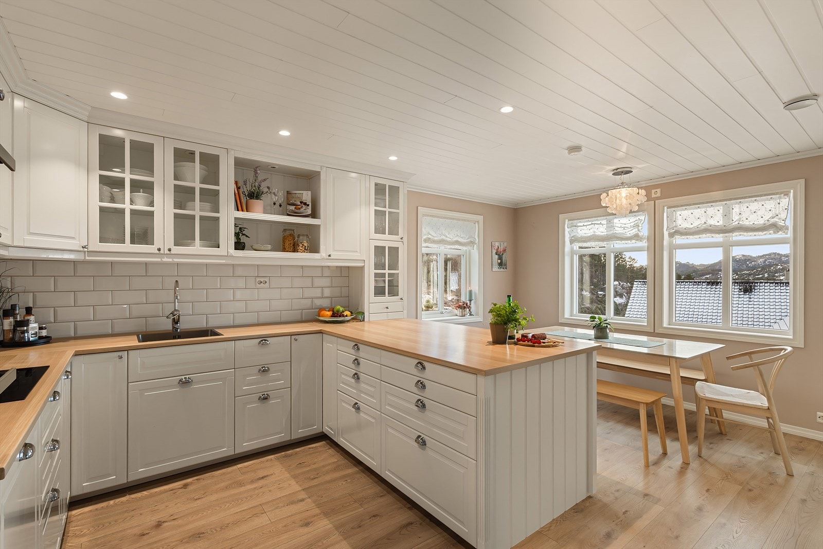 Lyst og tidløst kjøkken med hvite profilerte fronter og benkeplate av typen laminat. Galleribilde