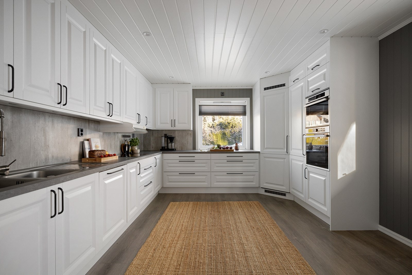 Det lekre kjøkkenet ble pusset opp i 2018 med innredning fra danske Aubo. Hvite profilerte fronter og sorte grep. Grå benkplate og grå vegger. Galleribilde