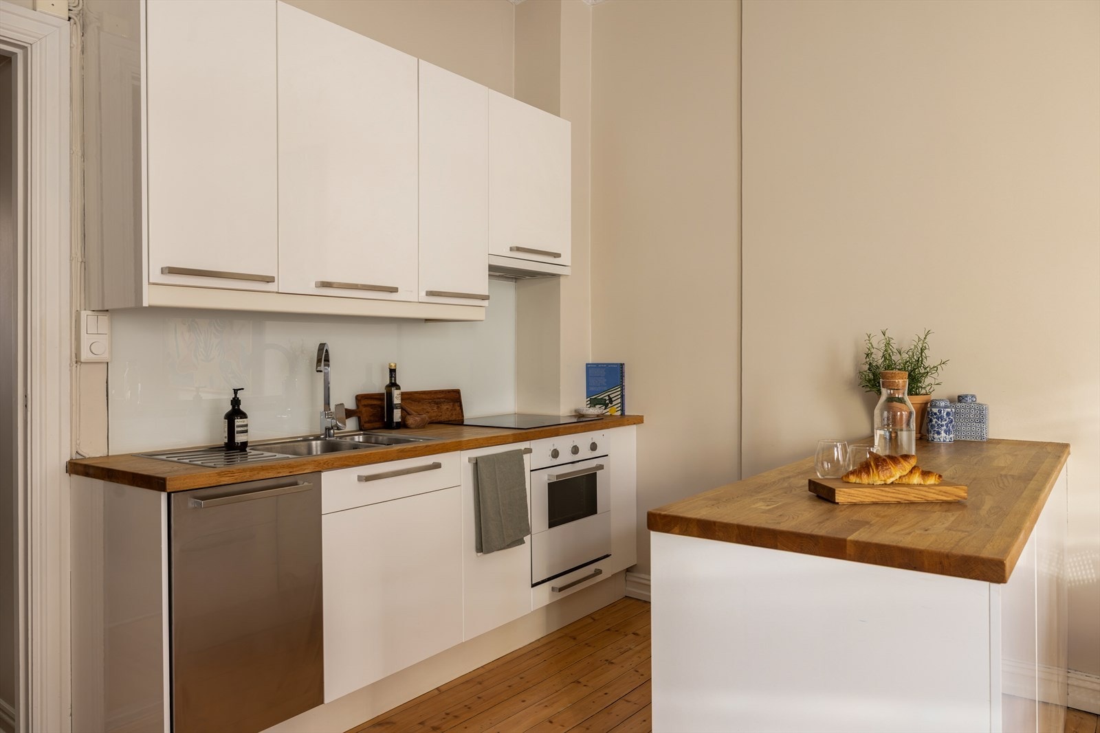 Leiligheten har et velutstyrt og tidsriktig kjøkken med lyse fronter og kjøkkenøy fra IKEA, som gir både ekstra benkeplass og en naturlig samlingsplass Galleribilde