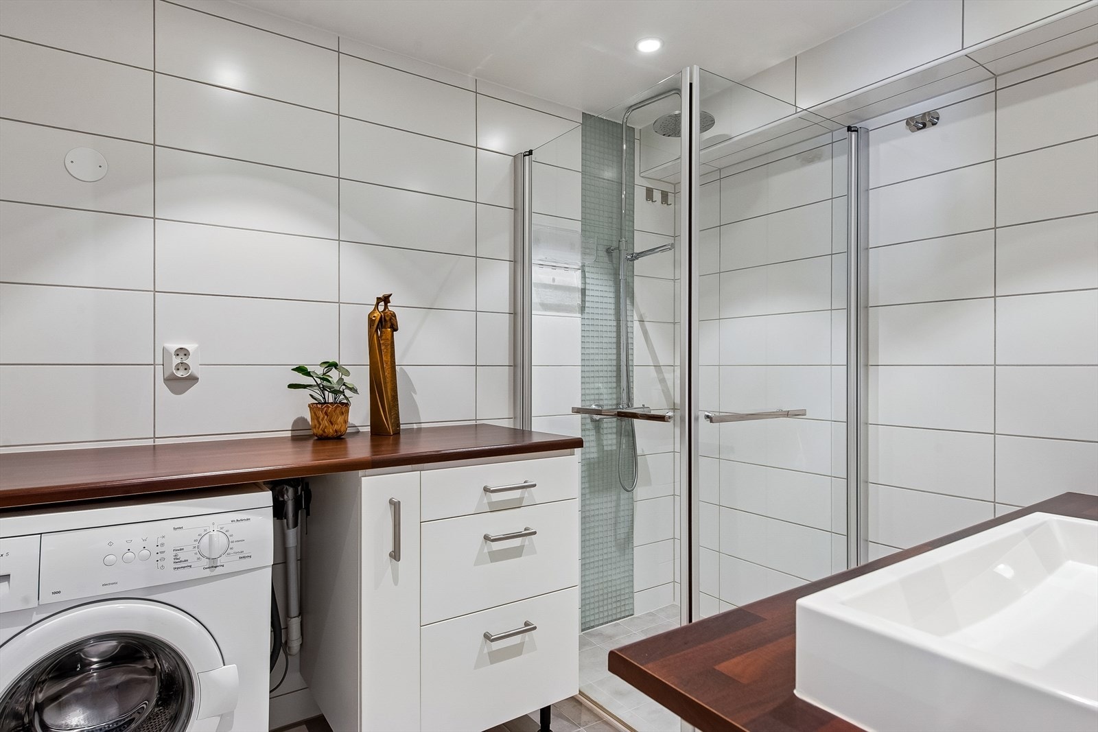 Badet er utstyrt med dusjhjørne med innfellbare vegger og opplegg for vaskemaskin. Galleribilde