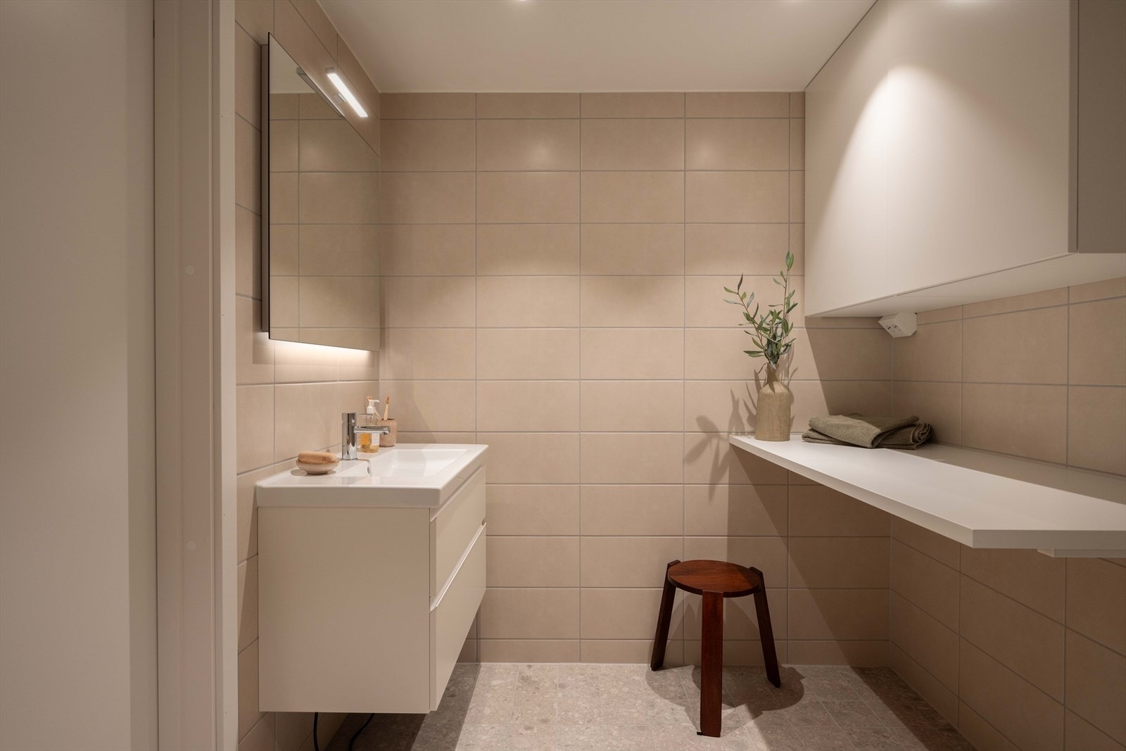 Baderommet har praktisk skap, servantskap og benk for oppbevaring. Galleribilde