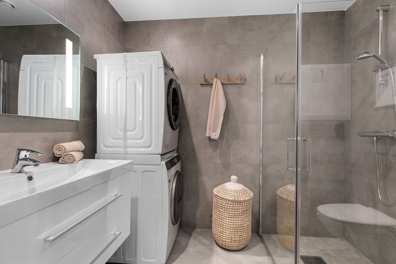 Praktisk bad i første etasje med flislagte overflater og opplegg for vaskesøyle. Galleribilde