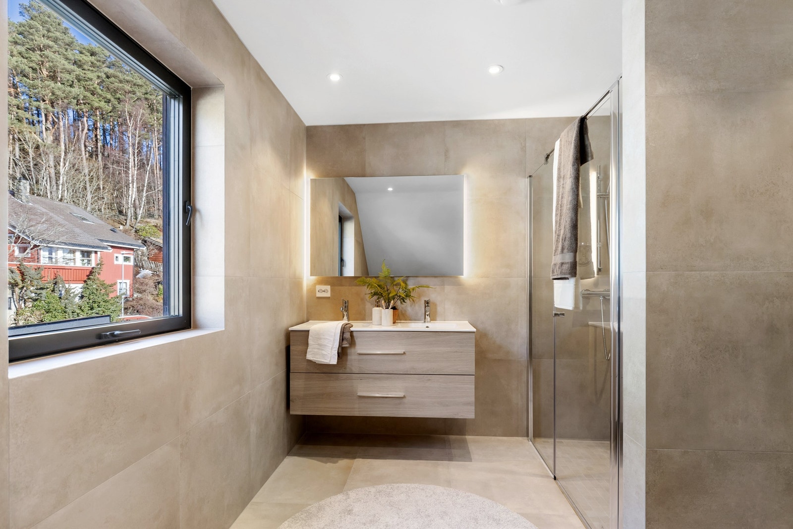 Hovedbadet er delikat flislagt og utstyrt med en bred servant med doble skuffer. Galleribilde